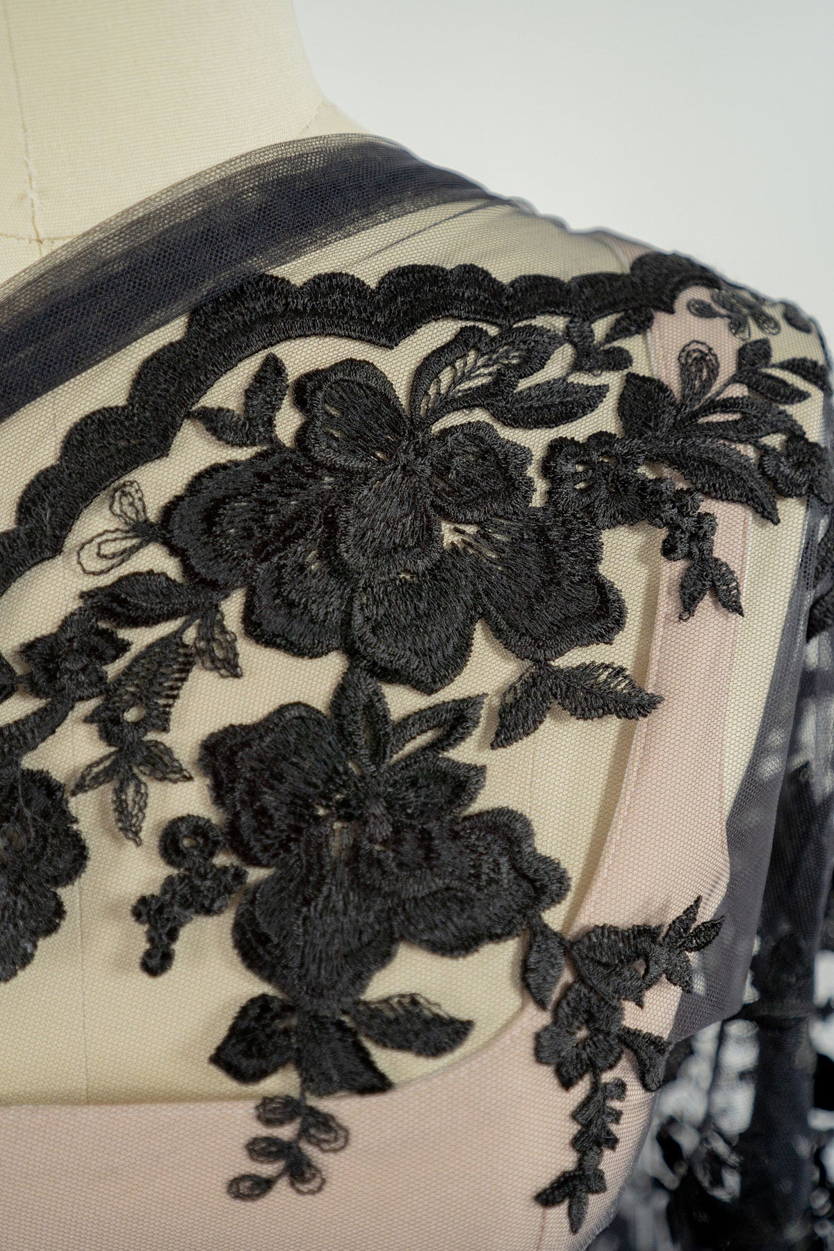 Detail der schwarzen Spitzenbordüre von L25-017BLK an der Schulter der Schneiderpuppe.